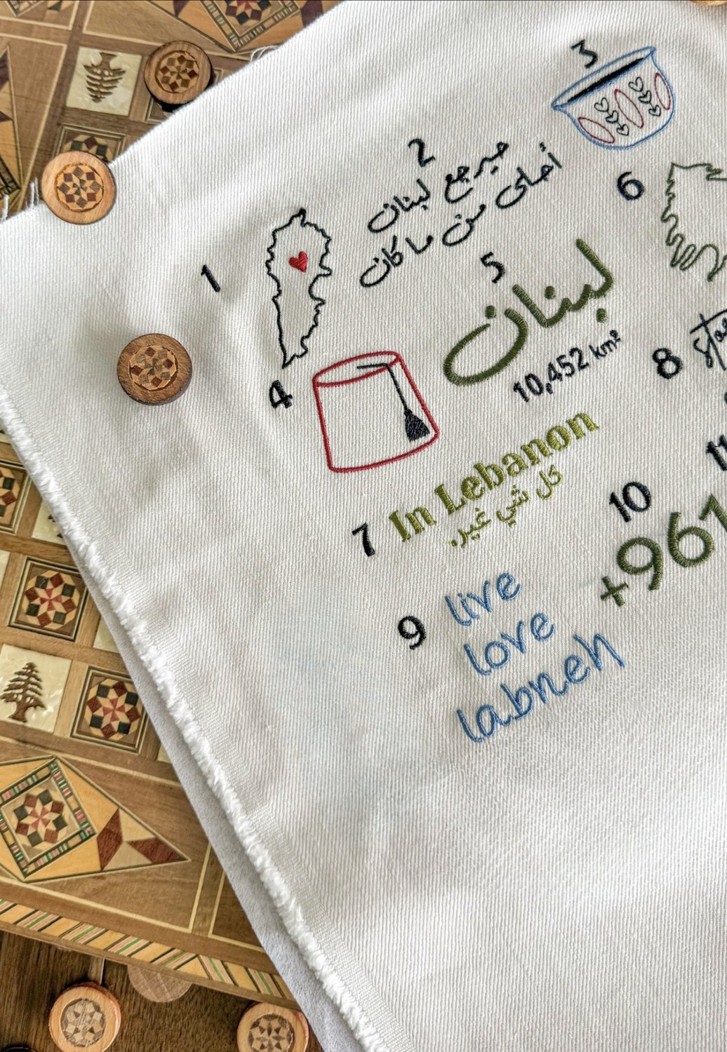 White Arabic embroidery menu featuring Lebanon lettering and colourful motifs