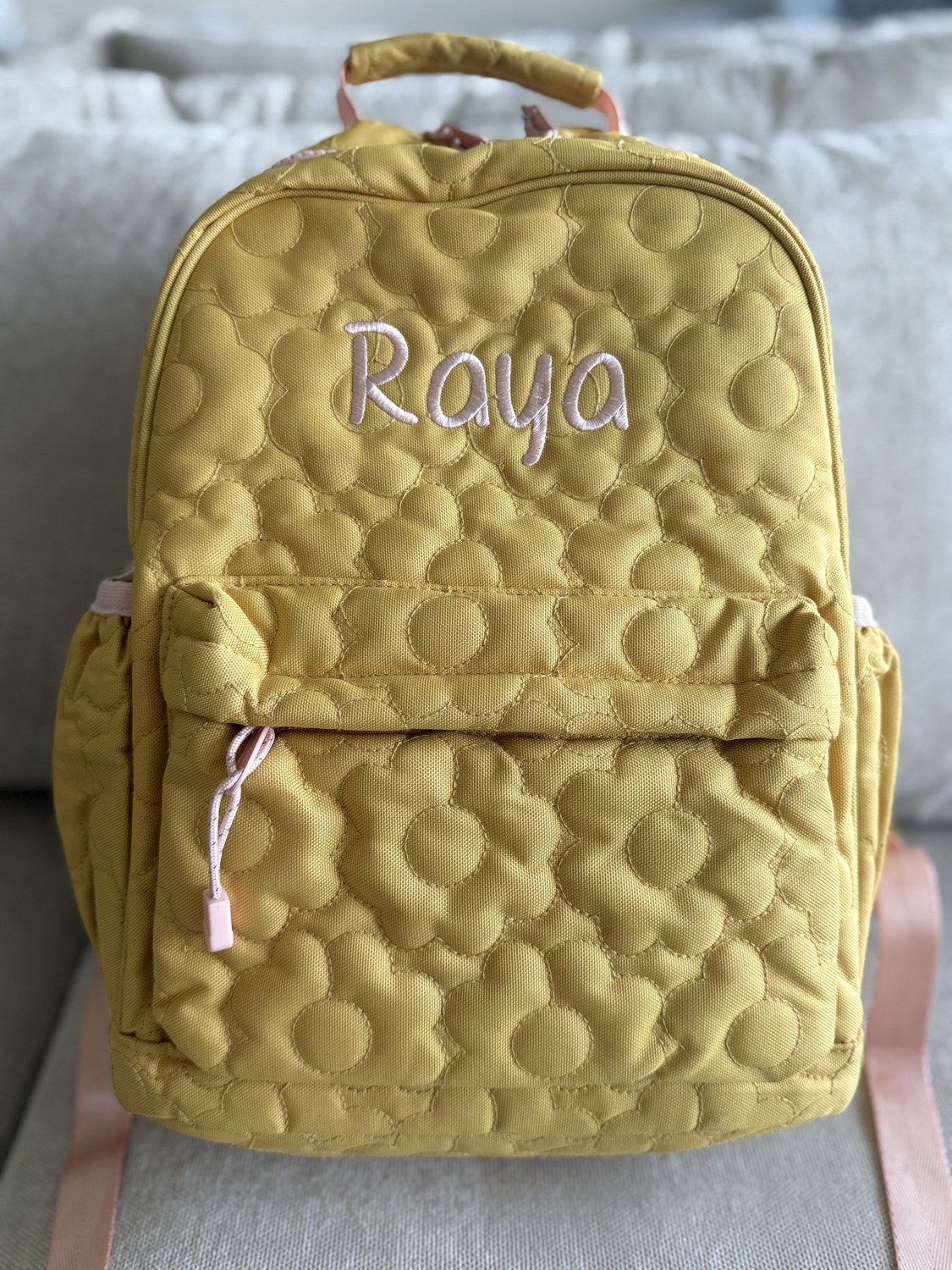 Yellow quilted backpack embroidered with Raya’s name