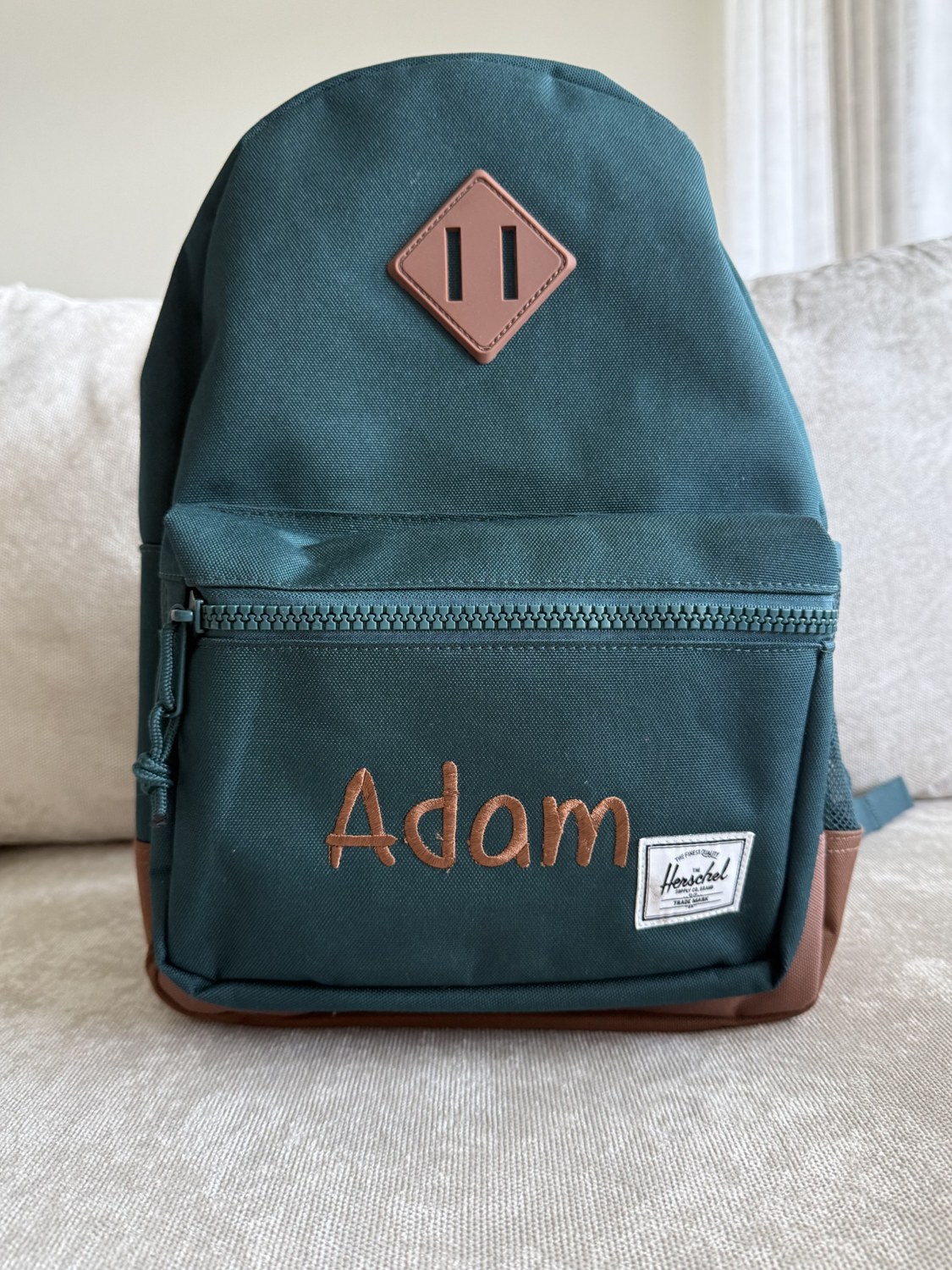 Teal backpack embroidered with Adam’s name